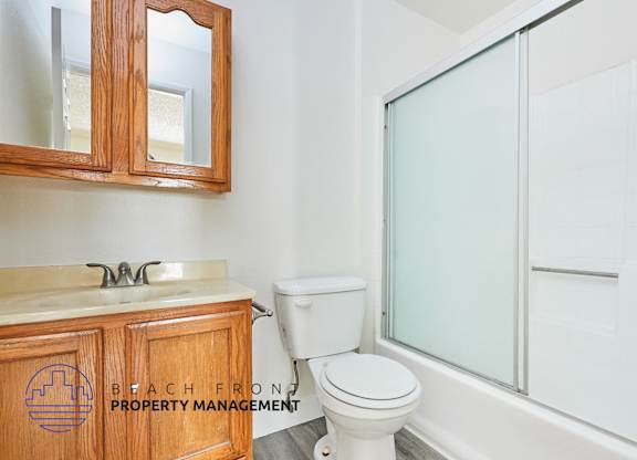 A bathroom with a toilet, sink, and mirror.