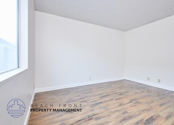 A room with wooden flooring and a logo for Beach Front Property Management.