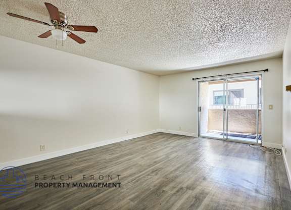 A room with a ceiling fan and a sliding glass door leading to a balcony.