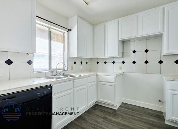 A kitchen with white cabinets and a black dishwasher.