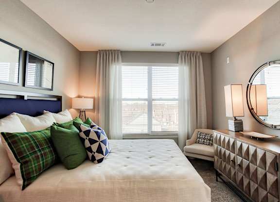 a bedroom with a large bed and a dresser with a mirror