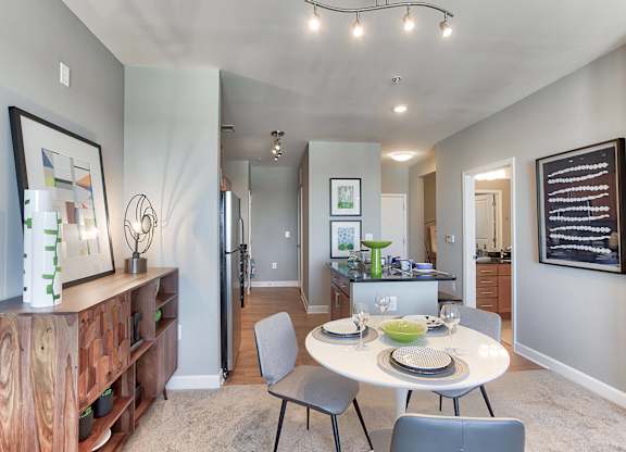a dining area with a table and chairs and a kitchen in the background