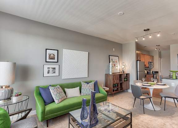 a living and dining room area with a green couch and a glass coffee table