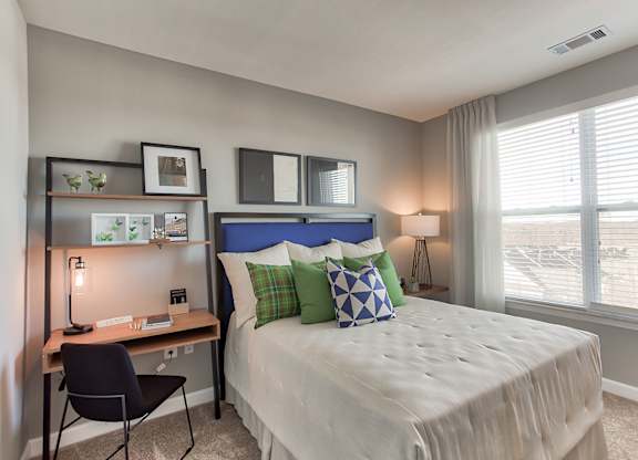 a bedroom with a large window and a desk with a chair