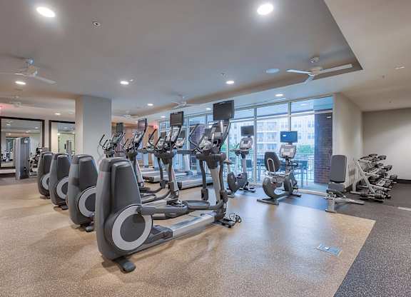 a spacious fitness center with cardio machines and a large window