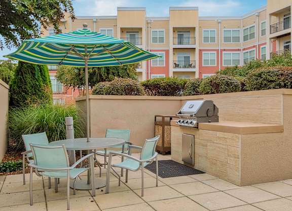 a patio with a grill and table and chairs