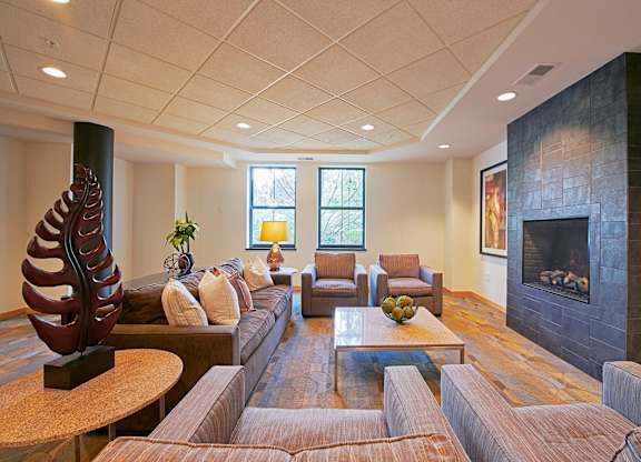 A living room with a sofa, chairs, a fireplace, and a large sculpture.