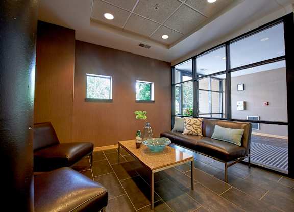 A seating area with a brown leather couch, brown leather chairs, and a coffee table.