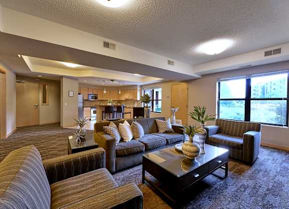 A living room with a brown couch, a coffee table, and chairs.