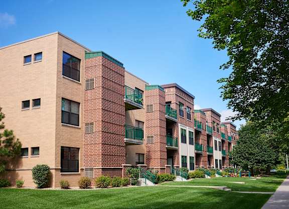 A large apartment building with balconies and a green lawn in front.