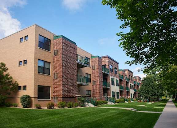 A large apartment building with balconies and a green lawn in front.