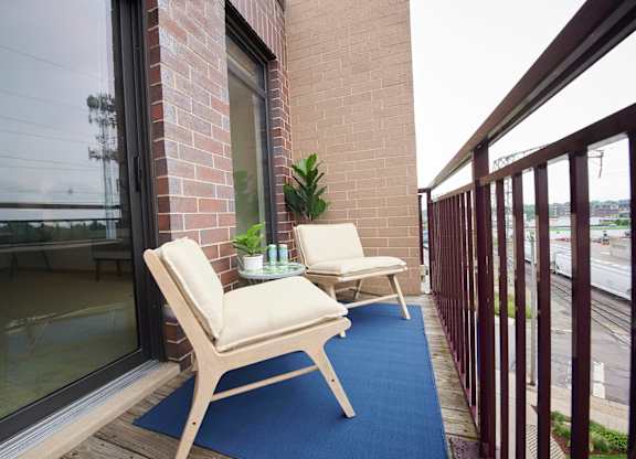 A balcony with a blue rug and two chairs.