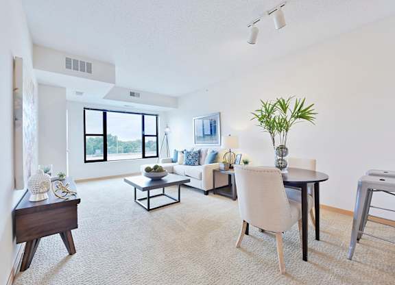 A living room with a white couch, a table, and a white chair.
