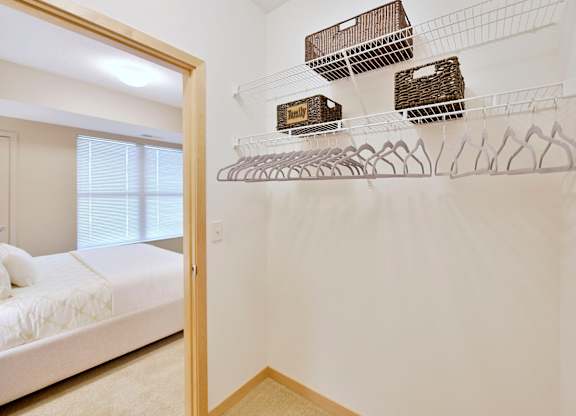 A white wall with wire shelves and baskets on it.