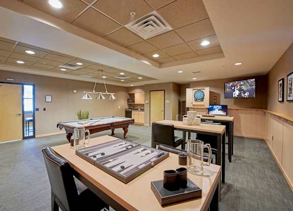 A conference room with a tables and chairs and a TV on the wall.