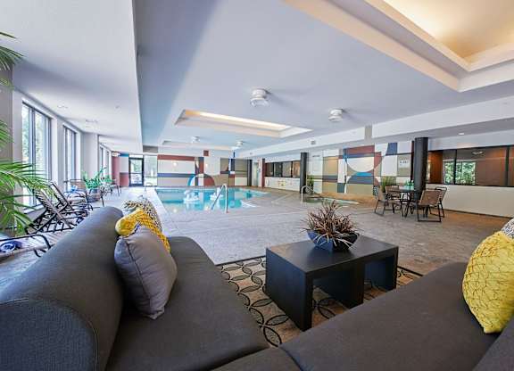 An indoor pool with a sofa, a table, and beach chairs.