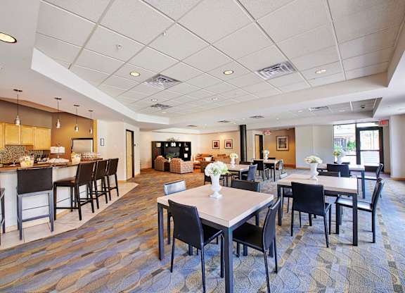 A large room with tables, chairs, and a bar area.