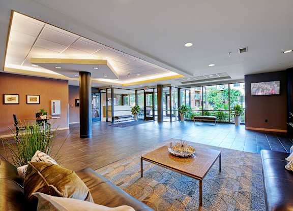 A lobby with a brown leather couch and a coffee table.