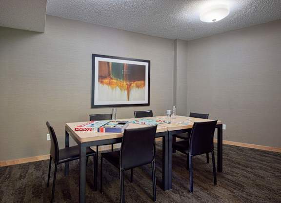A conference room with a table, chairs, and a painting on the wall.