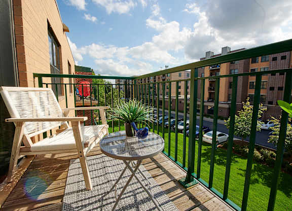 A balcony with a table and chair overlooking a green lawn.