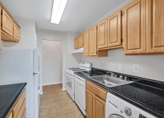 a kitchen with wood cabinets and black counter tops and white appliances
