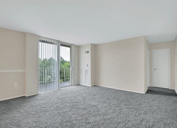 an empty living room with a sliding glass door to a balcony