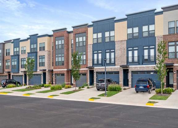 a row of new apartment buildings with cars parked in a parking lot