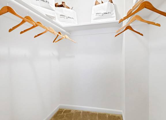 a walk in closet with shoe racks and bags on the wall