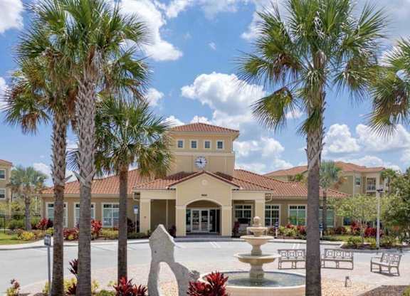 a courtyard with a fountain and palm trees in front of a building