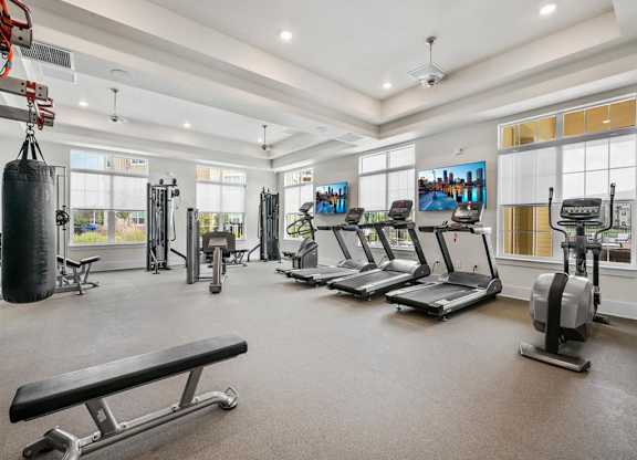 A spacious gym with treadmills, a punching bag, and a bench.