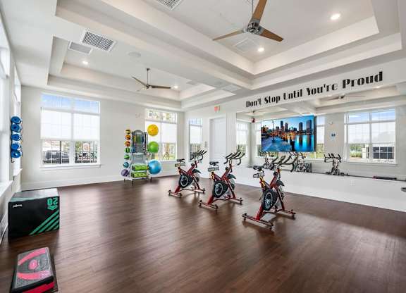 A gym with a row of stationary bikes and a motivational sign on the wall.