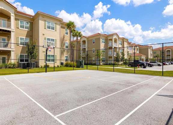 A basketball court in the foreground of a residential area with apartment buildings.