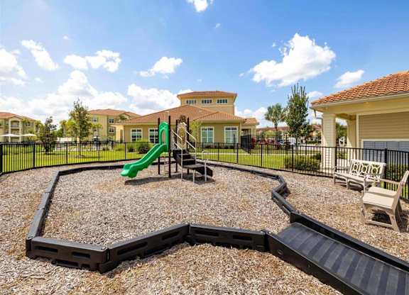 A playground with a green slide and a black railing.