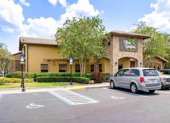 a parking lot in front of a restaurant with a van parked in front