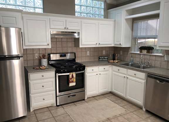 A kitchen with white cabinets and a stainless steel refrigerator.