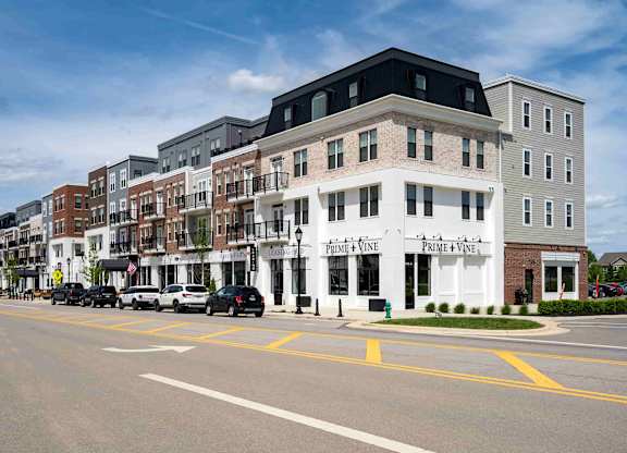 A street view of a row of buildings with cars parked in front.