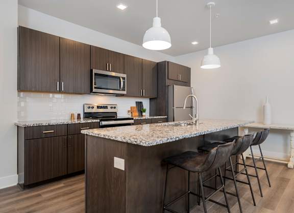 A kitchen with brown cabinets and a marble countertop.