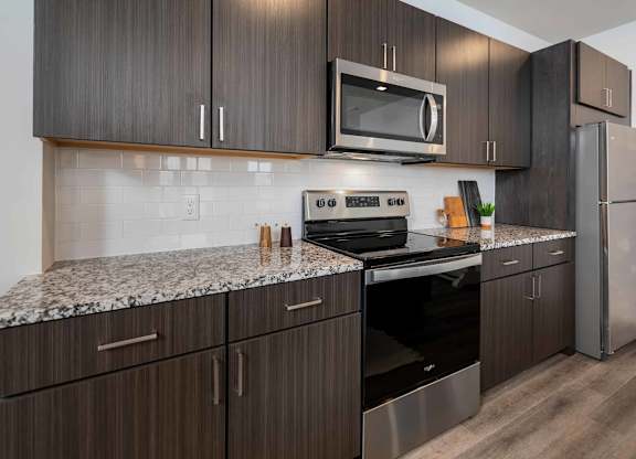 A kitchen with dark wood cabinets and stainless steel appliances.