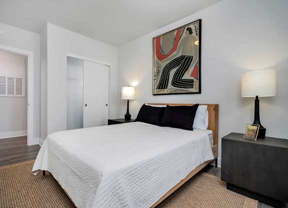 A bedroom with a large bed and a painting on the wall.