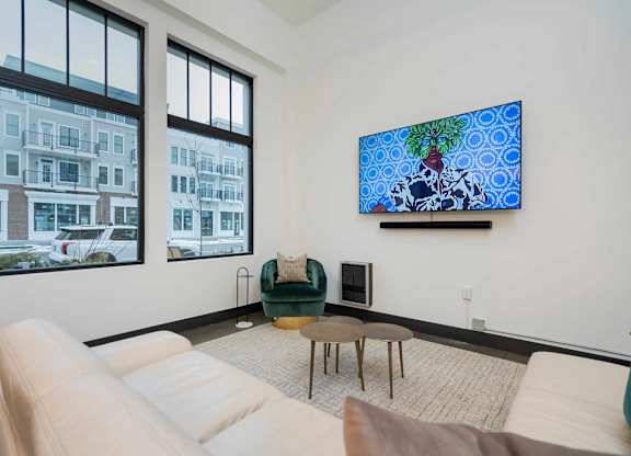 A living room with a white couch, a green chair, and a large painting on the wall.
