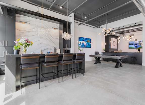 A modern bar area with a long counter and stools.