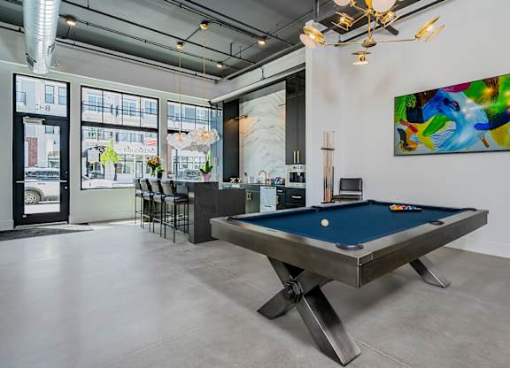 A pool table is in the middle of a room with a painting on the wall.