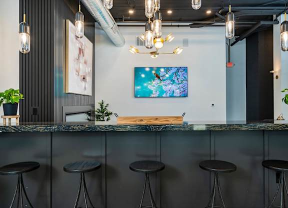 A bar with a blue painting on the wall and a plant on the counter.