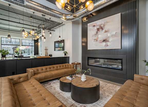 A modern living room with a fireplace and brown leather furniture.