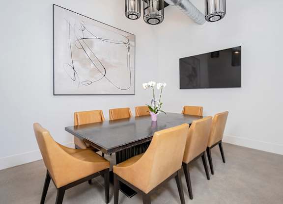 A dining table with chairs and a painting on the wall.