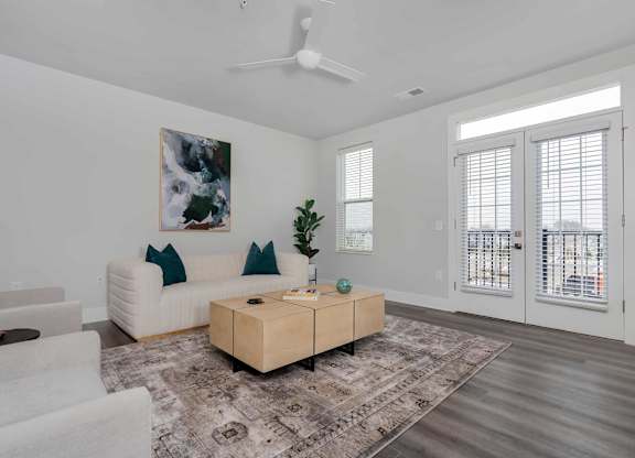 A living room with a white couch, a wooden coffee table, and a painting on the wall.