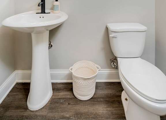 A white pedestal sink with a mirror above it and a white toilet next to it.