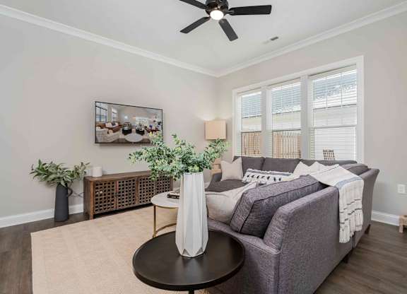 A living room with a grey couch, a coffee table, and a ceiling fan.