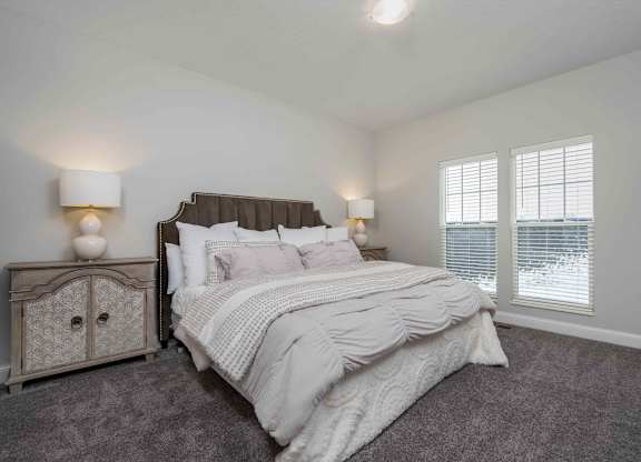 A bedroom with a large bed and a nightstand with a lamp.