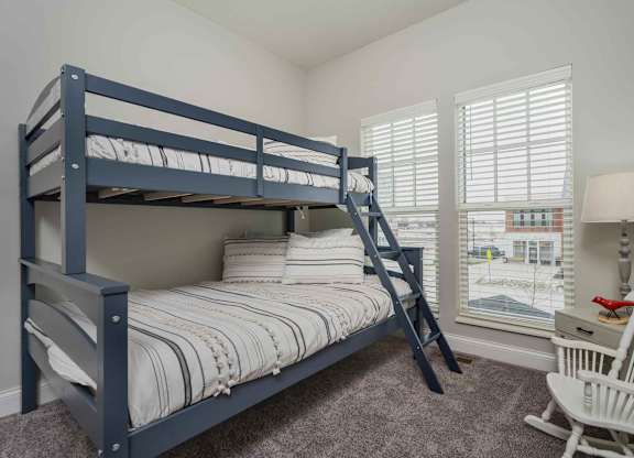 A bedroom with a bunk bed and a chair.